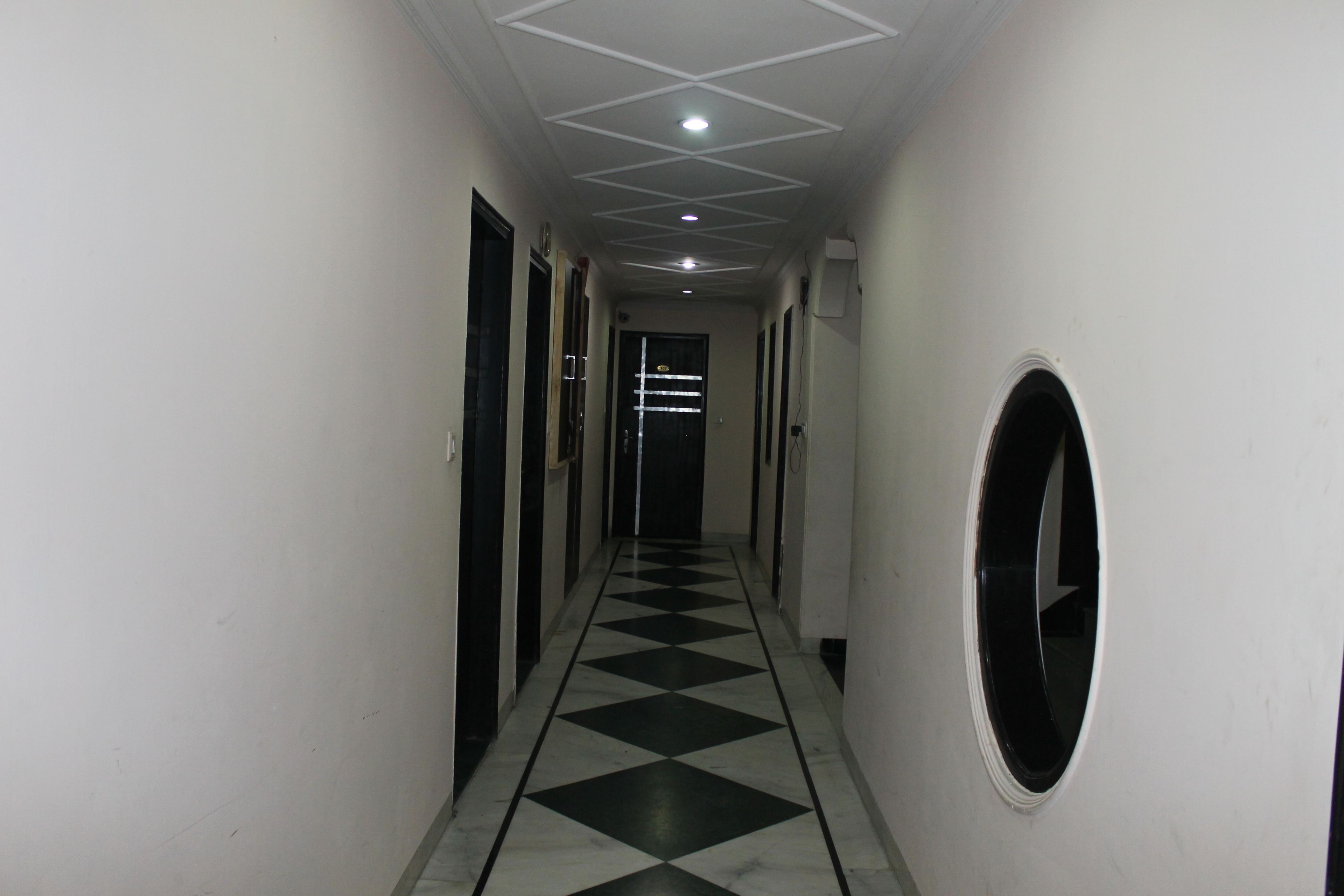 A hallway with a checkered floor, white walls, and doors on both sides.
