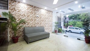 Una zona de recepció amb un sofà a ratlles, una taula d'informació turística i una paret amb un dibuix arrugat.