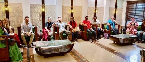 A group of people seated in a lobby with modern furniture and a stone wall backdrop.