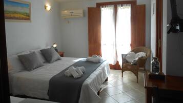 Una camera d'albergo con un letto grande, una sedia, un tavolino e un quadro appeso al muro.
