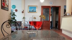 A dining area with a granite table, a glass of red wine, and a framed picture on the wall. - Hotel VelaSole (Siniscola)