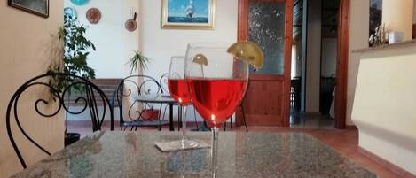 Un comedor con una mesa de granito, una copa de vino tinto y un cuadro en la pared.