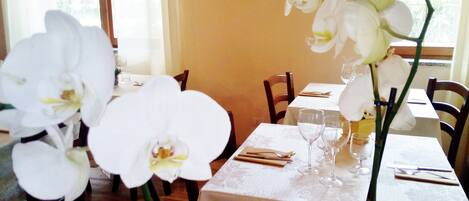 A dining table set with white tablecloth, glassware, and a single orchid.