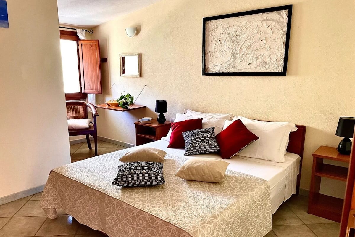 A neatly arranged hotel room with a bed, bedside tables, a desk, and a chair.