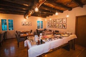 Comedor con mesas de buffet, vigas de madera en el techo e impresiones botánicas enmarcadas en la pared.