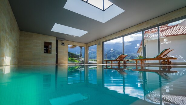 Una gran piscina interior con paredes de vidrio transparente y vistas a montañas.