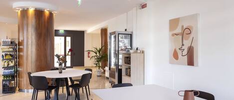 Un comedor moderno con una mesa redonda, sillas negras y un mantel blanco.