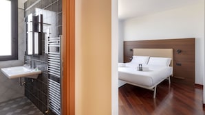 A modern bathroom with a sink, towel rack, and a large mirror. The room has a wooden floor and a window. - B&B Hotel Sassuolo (Sassuolo)