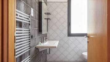 A modern bathroom with a glass shower enclosure, a sink, and a toilet.