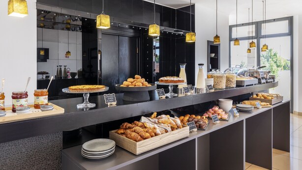 A buffet counter with various pastries and desserts, including croissants and cakes, displayed on trays and stands. - B&B Hotel Sassuolo (Sassuolo)