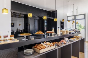 A buffet counter with various pastries and desserts, including croissants and cakes, displayed on trays and stands. - B&B Hotel Sassuolo (Sassuolo)