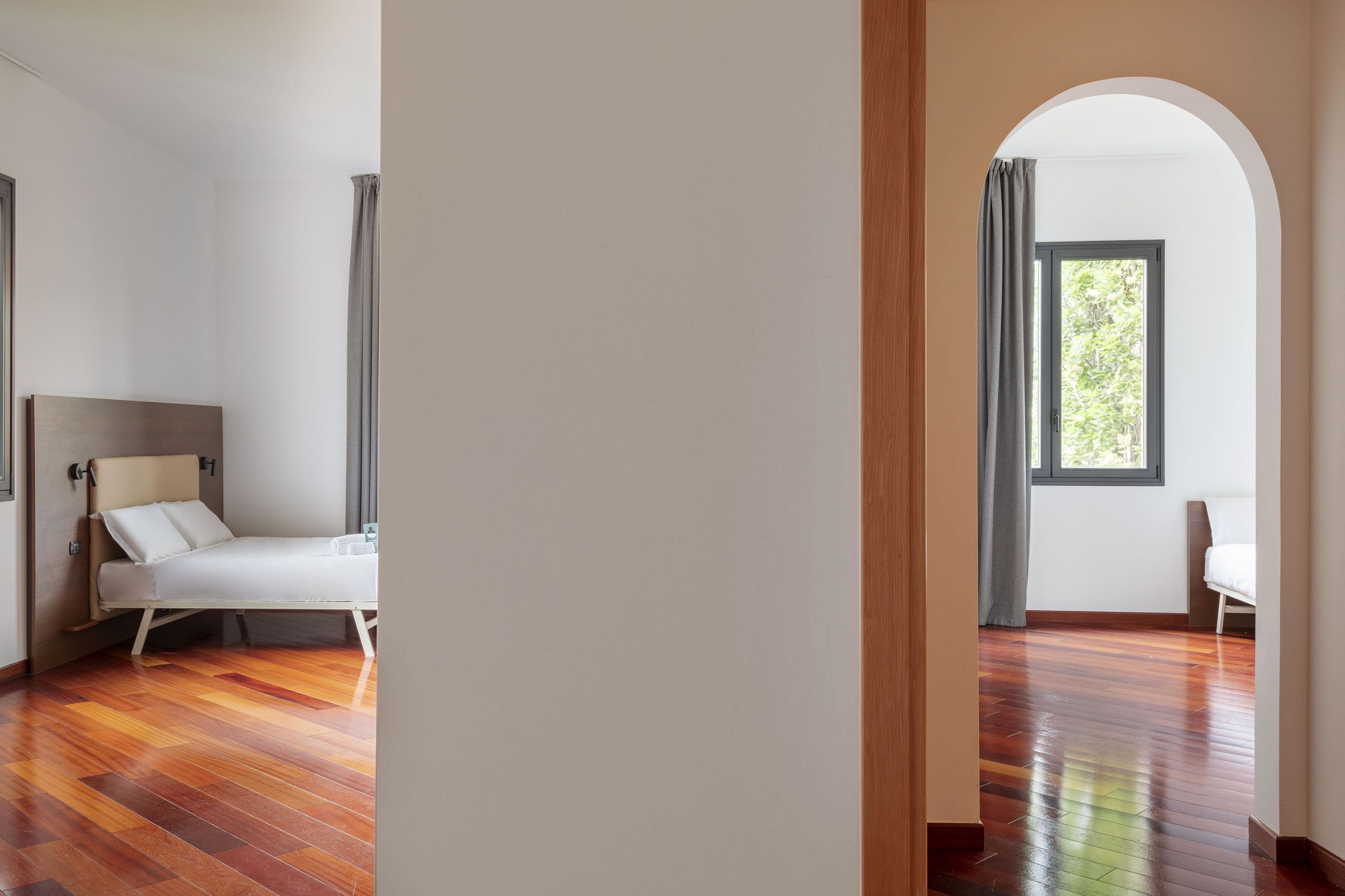 A modern room with a bed, a window with a view, and a wooden floor.