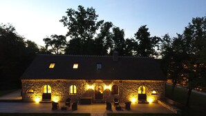 Un edificio de piedra con múltiples ventanales arqueados y una entrada central, iluminado con una luz cálida.
