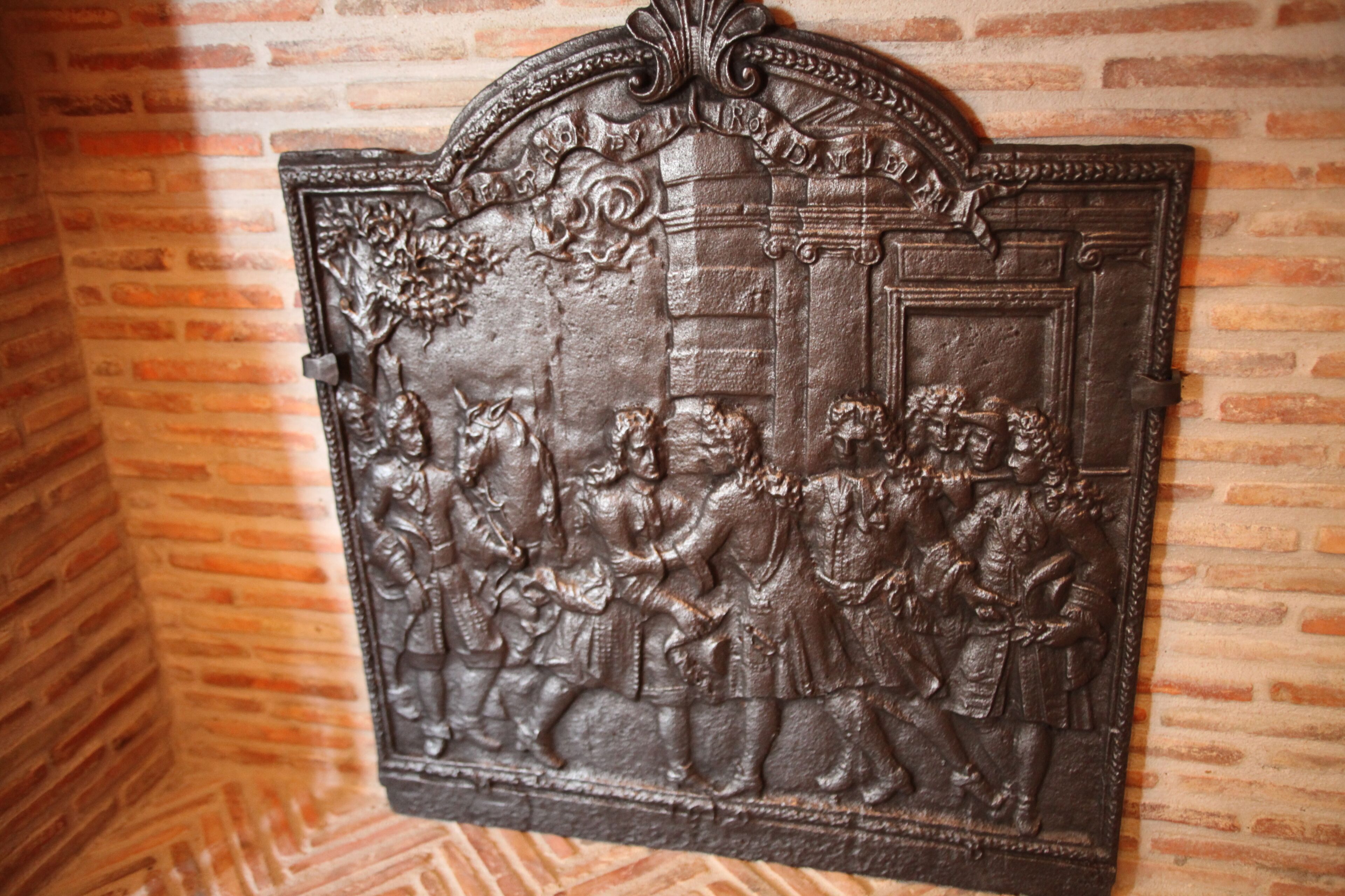 A detailed metal relief sculpture on a brick wall.