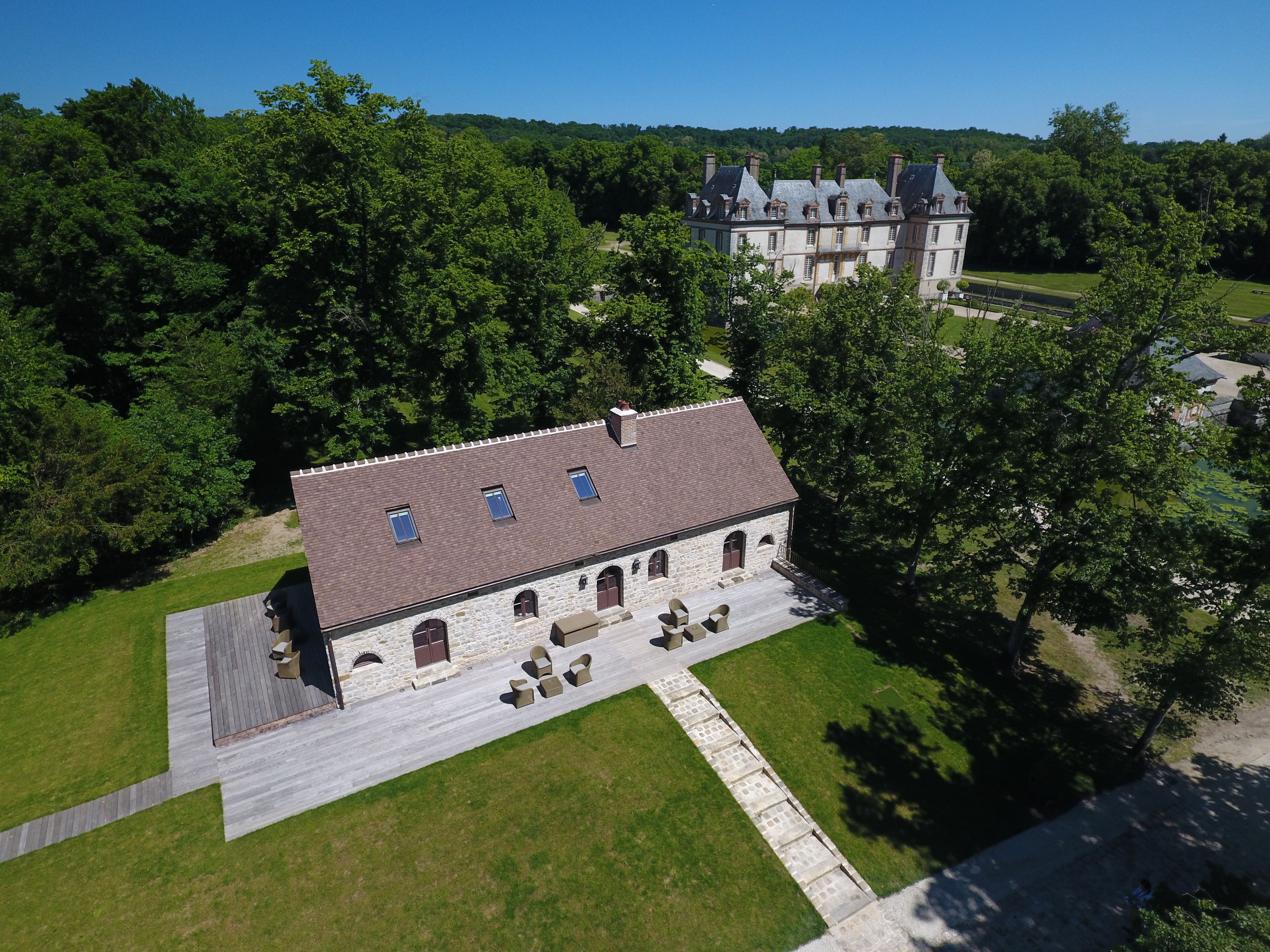 A large stone building with a tiled roof, surrounded by a well-maintained lawn and trees.