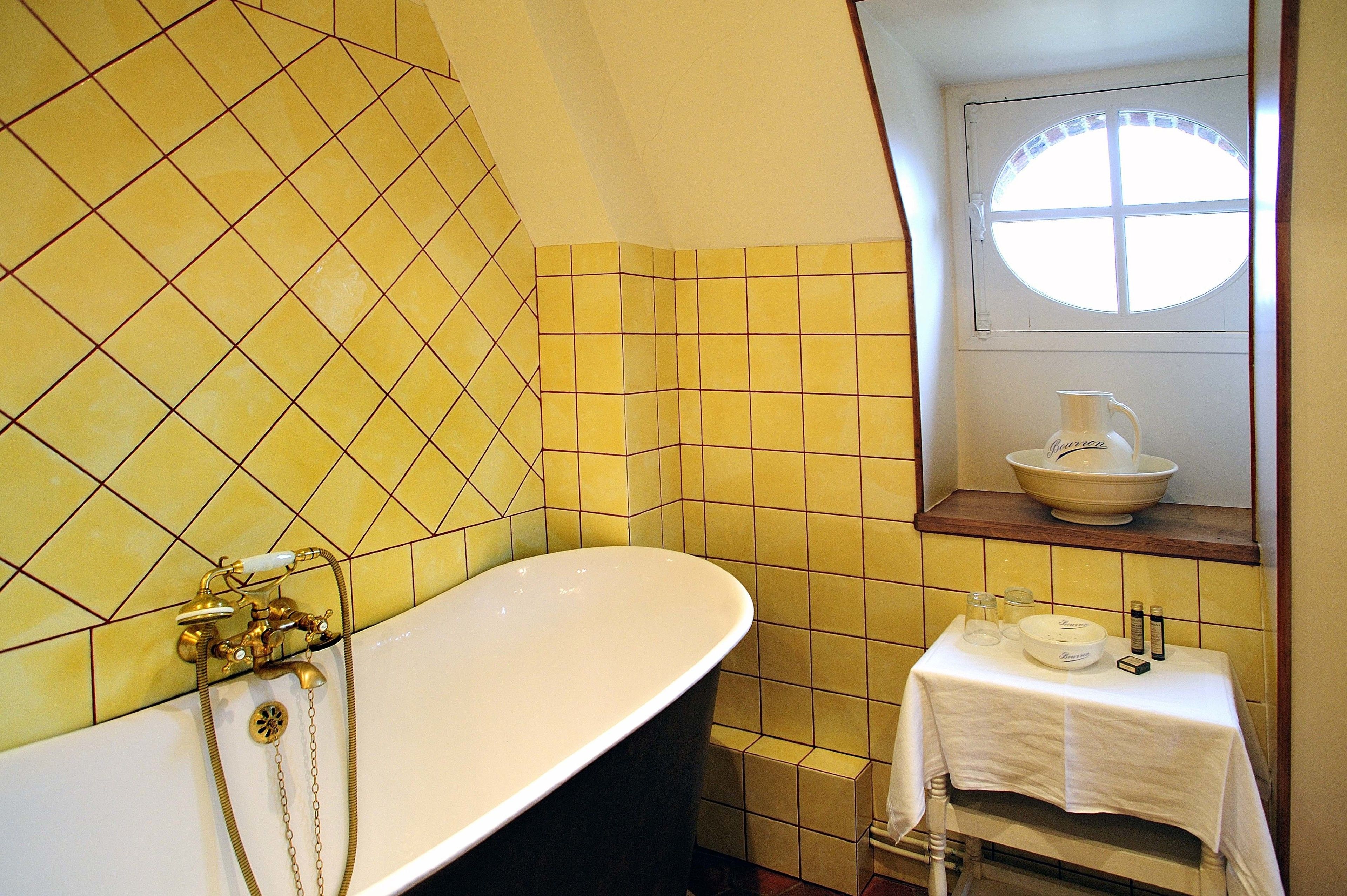 A bathroom with a freestanding bathtub, a window with a view, and a small table with toiletries.