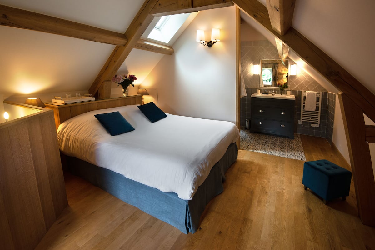 A bedroom with a large bed, a vanity with a mirror, and a small stool.