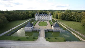 A large, symmetrical building with a central courtyard, surrounded by manicured lawns and water features.