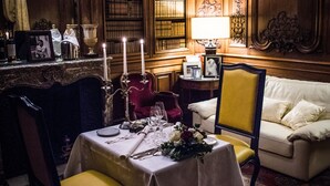 Un comedor formal con una mesa dispuesta para cuatro, rodeado de paneles de madera decorativos y estanterías.