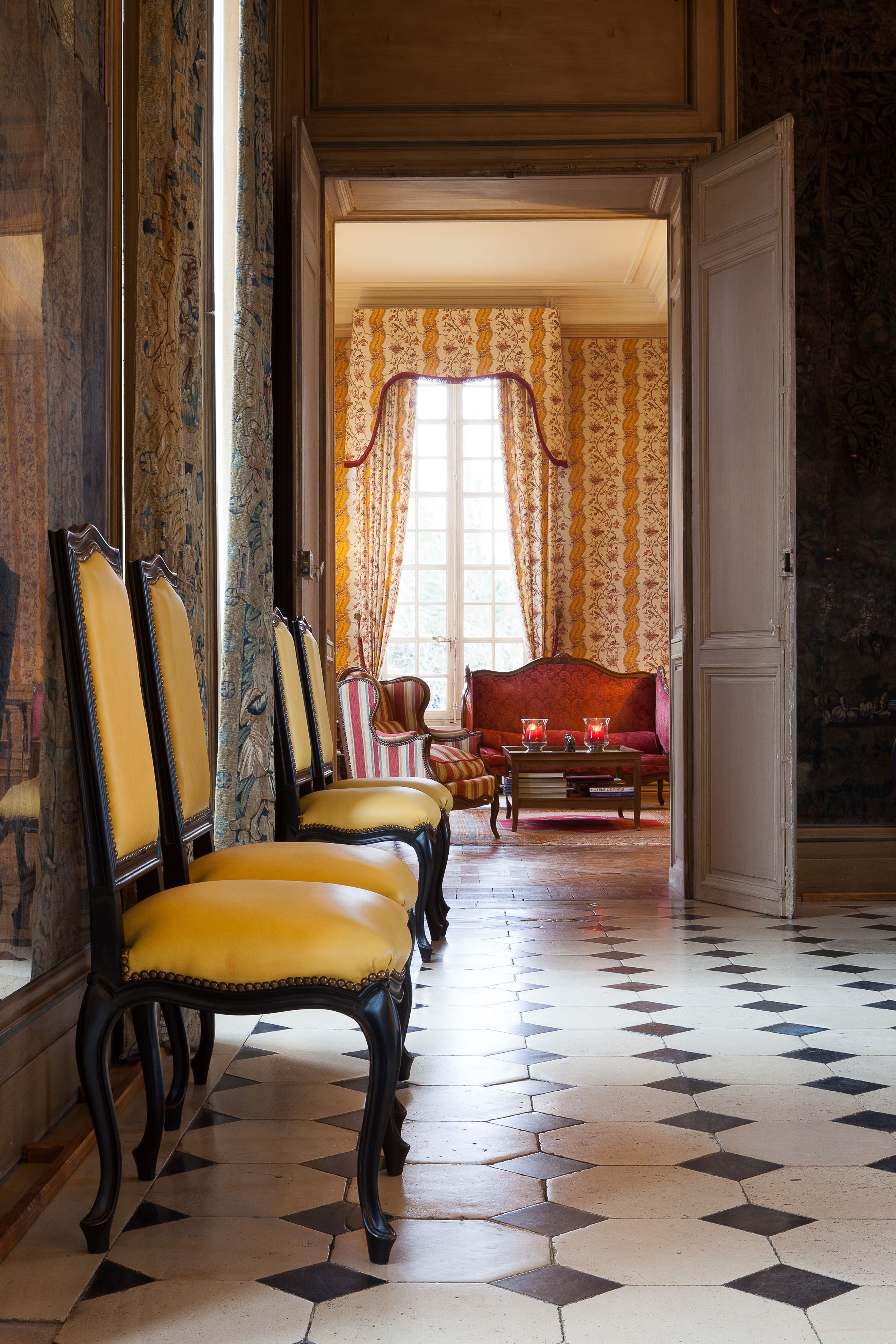 A room with a checkered floor, a red sofa, and a row of yellow chairs.