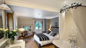 Una habitación de hotel con cama, baño con bañera, escritorio y silla.