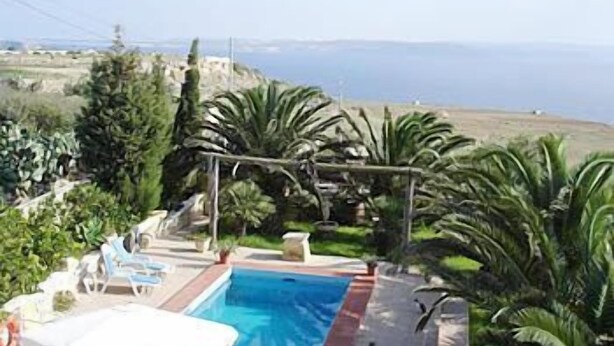A pool area with lounge chairs and a view of the sea. - Villa Veduta (Ghajnsielem)