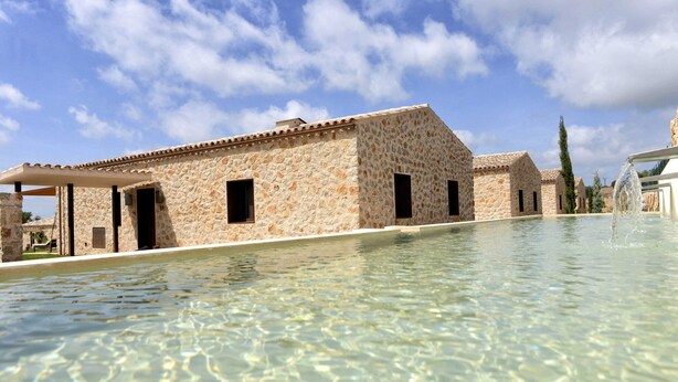 Un bâtiment en pierre avec une piscine devant.