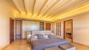 Une chambre moderne avec un grand lit, une armoire intégrée et une salle de bain équipée d’un miroir et d’un lavabo.