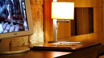 A hotel room with a wooden desk, a television, a lamp, and a chair.