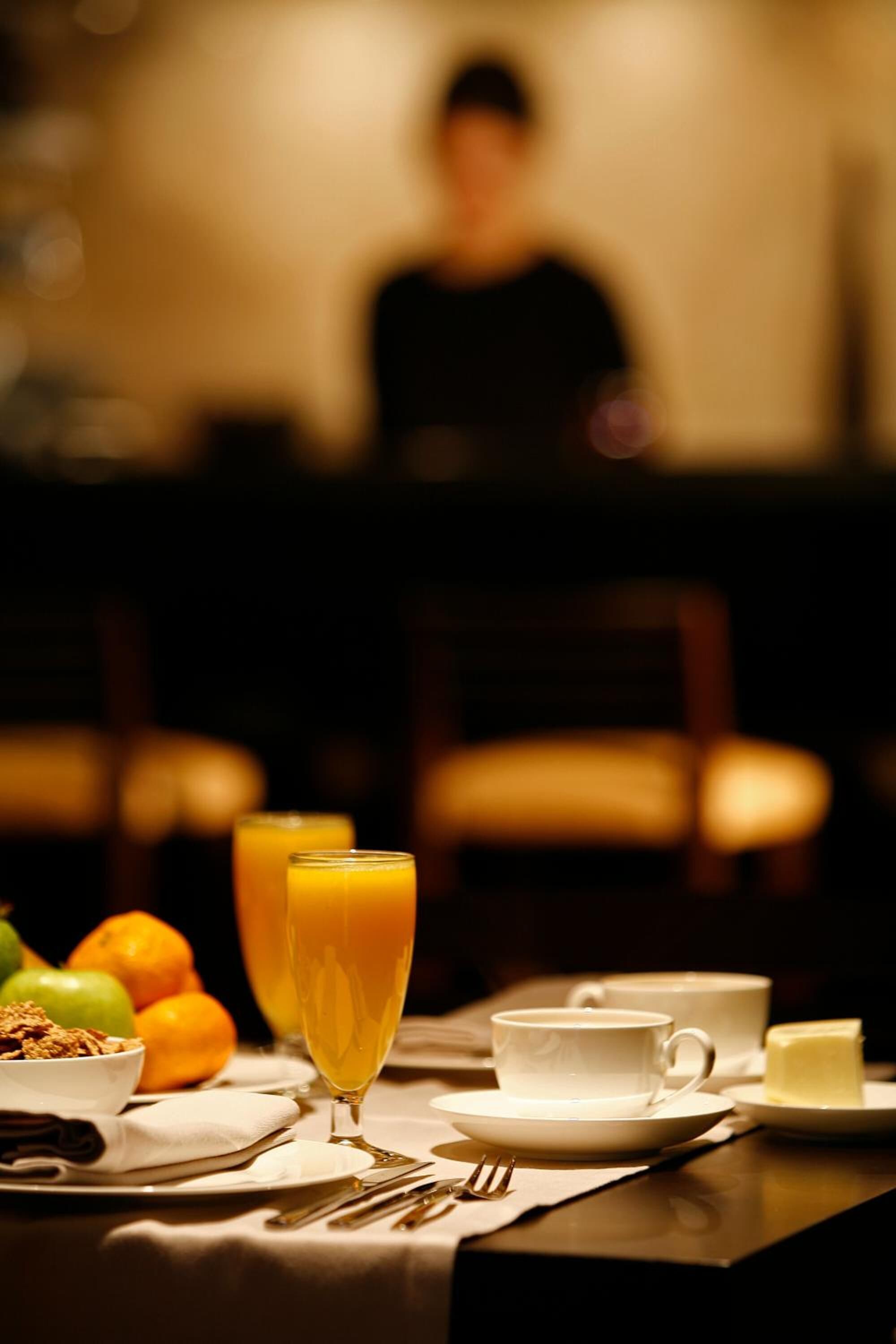 A breakfast table with a glass of orange juice, a cup of coffee, and a plate of butter.