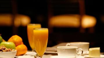 A breakfast table with a glass of orange juice, a cup of coffee, and a plate of butter.