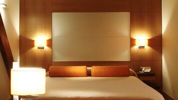A hotel room with a stone wall, wooden ceiling, a bed with orange pillows, bedside lamps, a tray with a teapot, cups, a newspaper, and an apple.