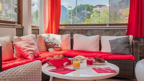 Cómoda zona de estar con sofá de mimbre y una mesa redonda, con desayuno incluido y vistas a las montañas.