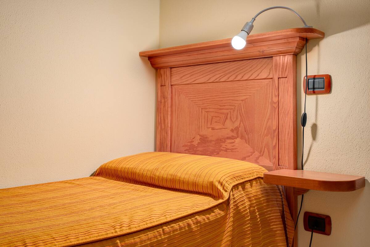 A bedroom with a wooden headboard, a bedside table, and a lamp.