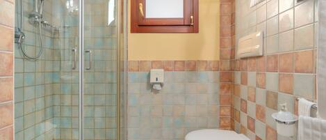 A bathroom with a glass-enclosed shower, a toilet, and a towel rack.