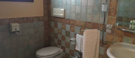 A bathroom with a toilet, bidet, sink, and a mirror.