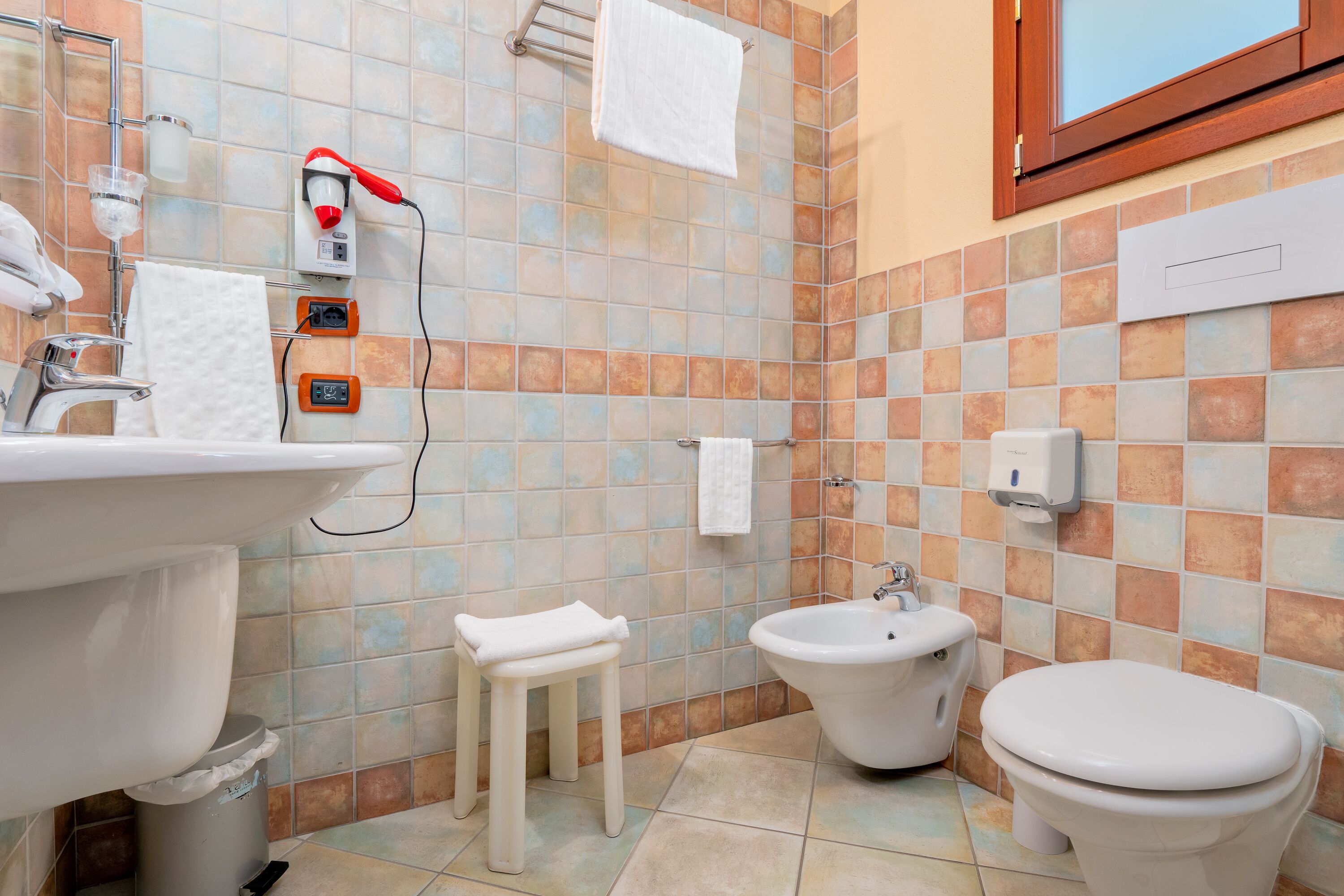 Un bany amb rentapans, vàter, bidet i un petit tamboret.