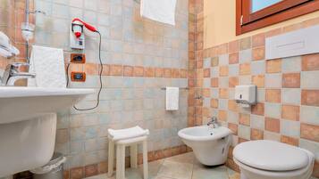 Un baño con lavamanos, inodoro, bidé y un pequeño taburete.