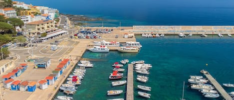 A marina with boats docked, a pier, and buildings with red roofs.
