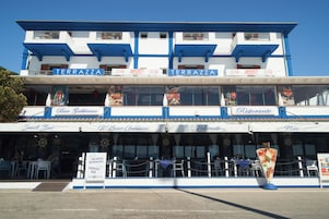 Un restaurante frente al agua con terraza y varias opciones de comida, incluyendo un bar y una pizzería.
