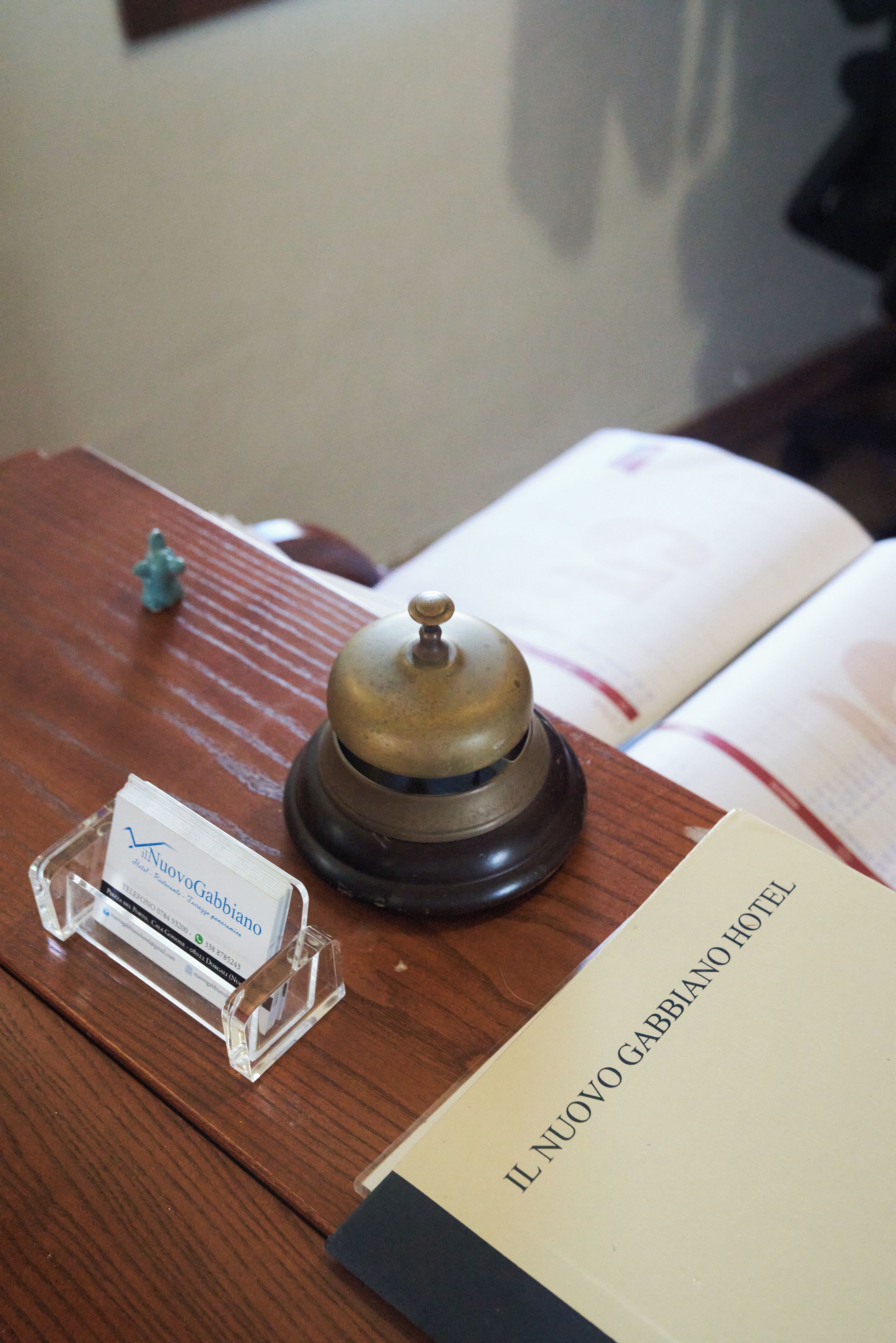 A wooden desk with a telephone, a name card, and a book titled 'IL NUOVO GABBIANO HOTEL'.