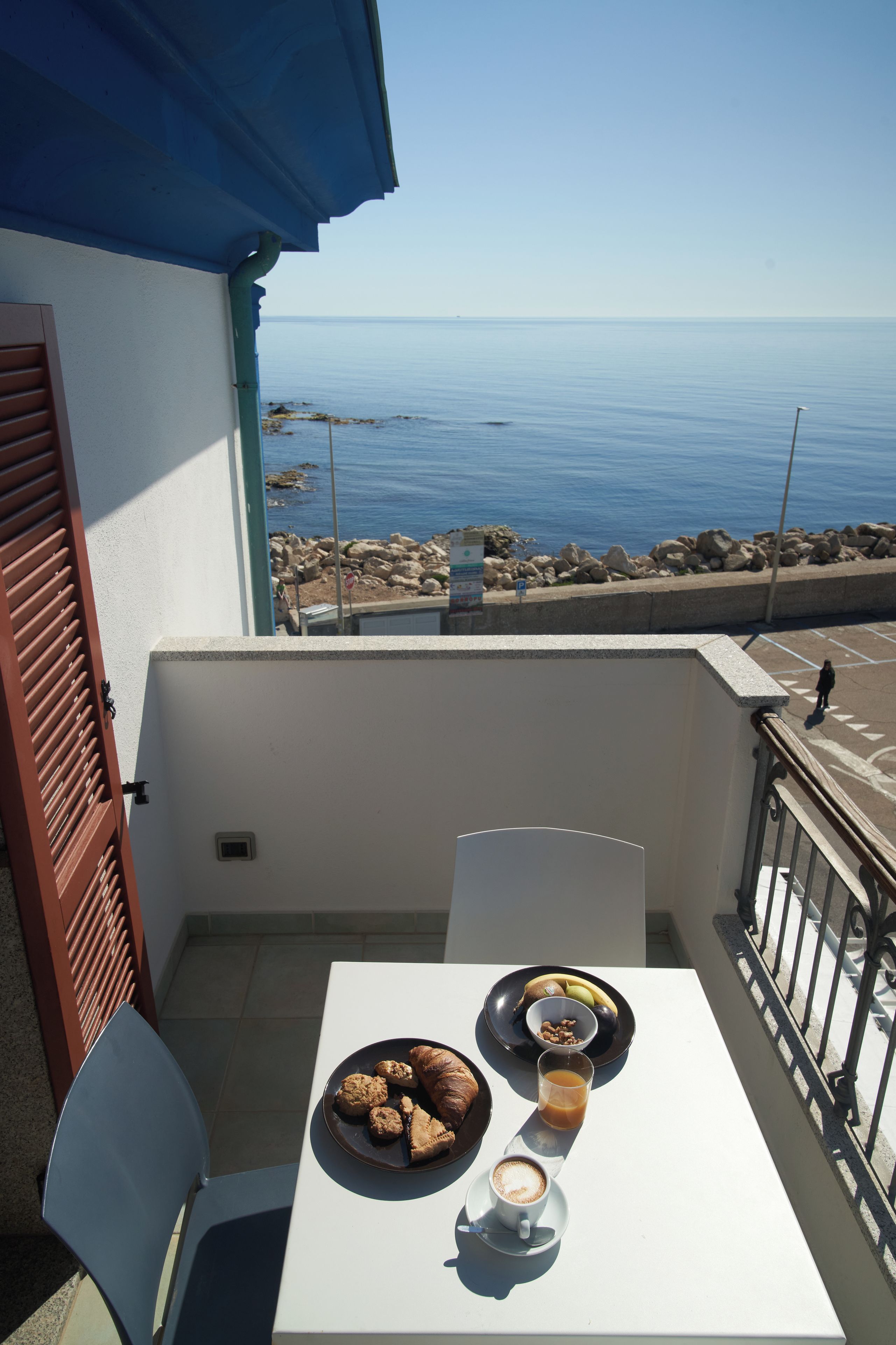 A balcony with a table set for breakfast, overlooking a coastal view.