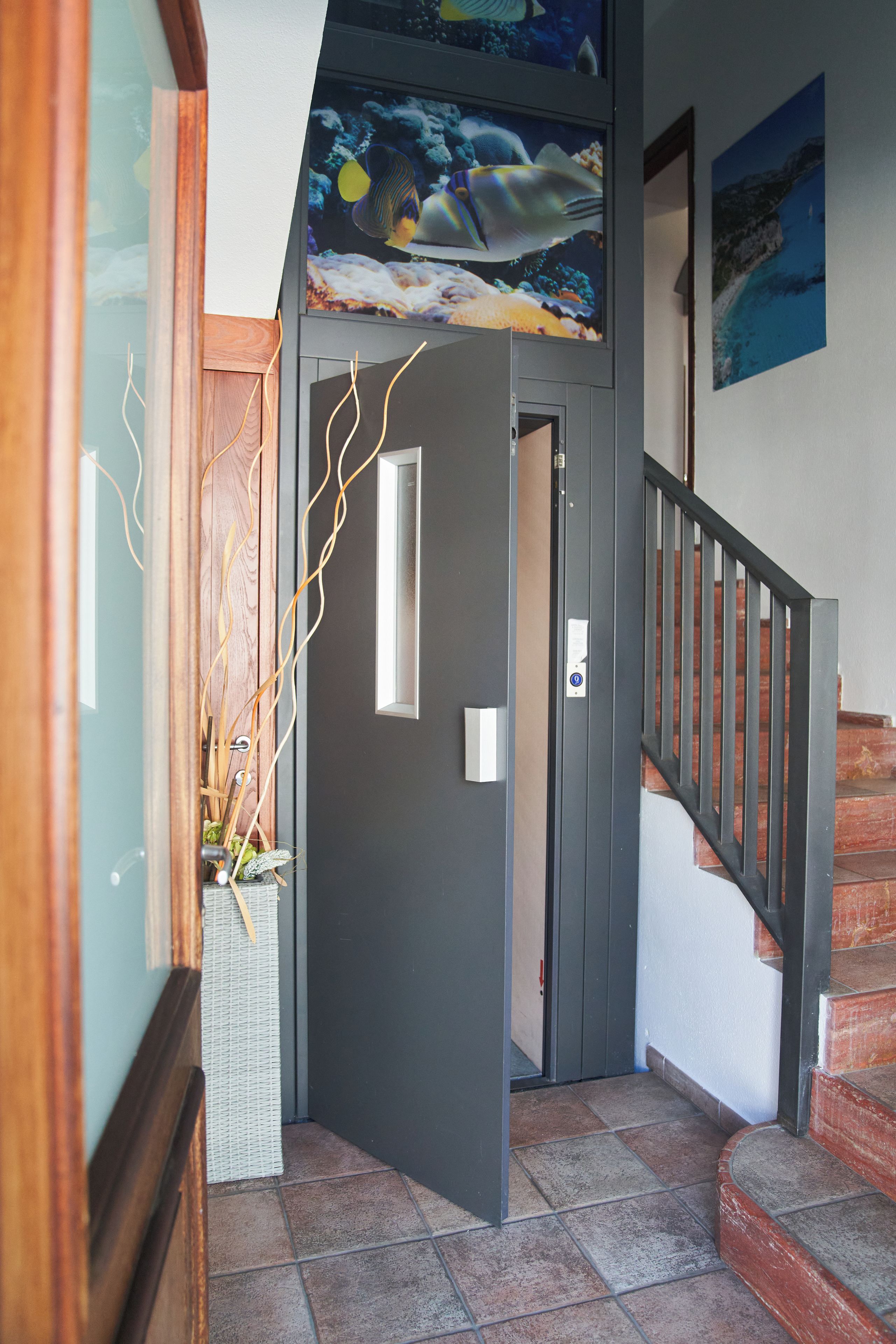 A staircase with a handrail, a door with a light switch, and a wall with a framed picture.