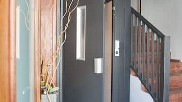 A staircase with a handrail, a door with a light switch, and a wall with a framed picture.