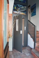 Una escalera con barandilla, una puerta con interruptor de luz y una pared con un cuadro enmarcado.