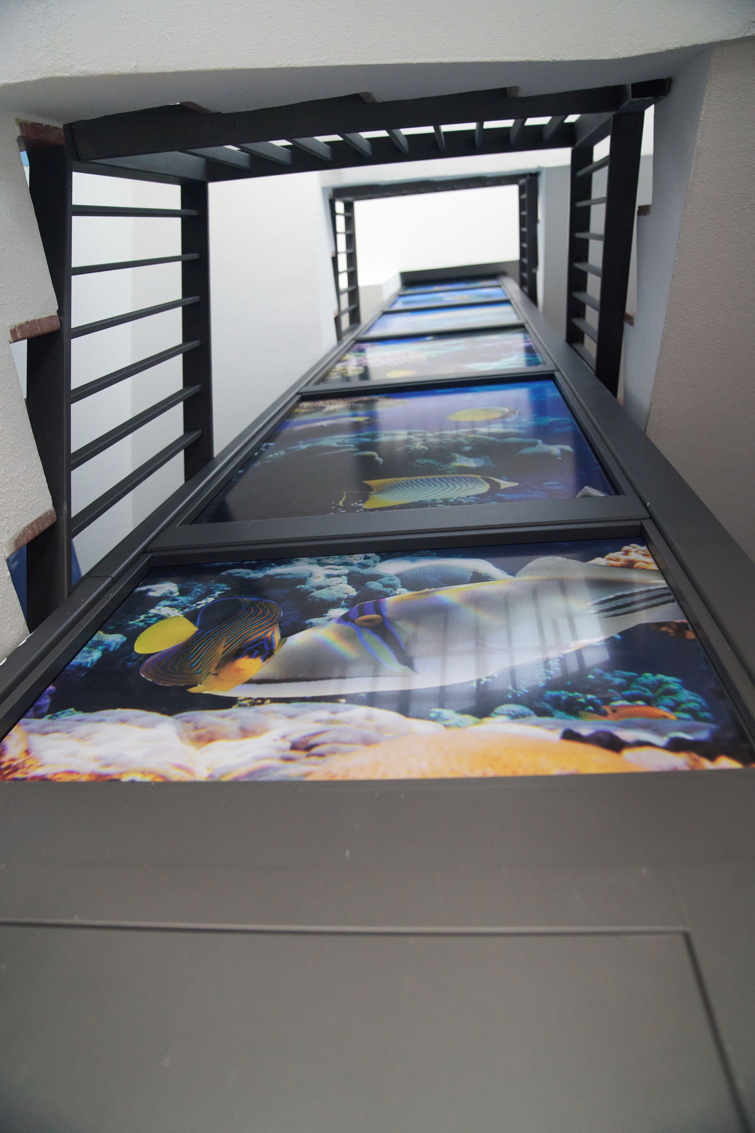 A corridor with a railing and a floor with a colorful, reflective surface.