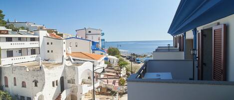 A coastal town with white buildings, a clear blue sky, and the sea in the background.