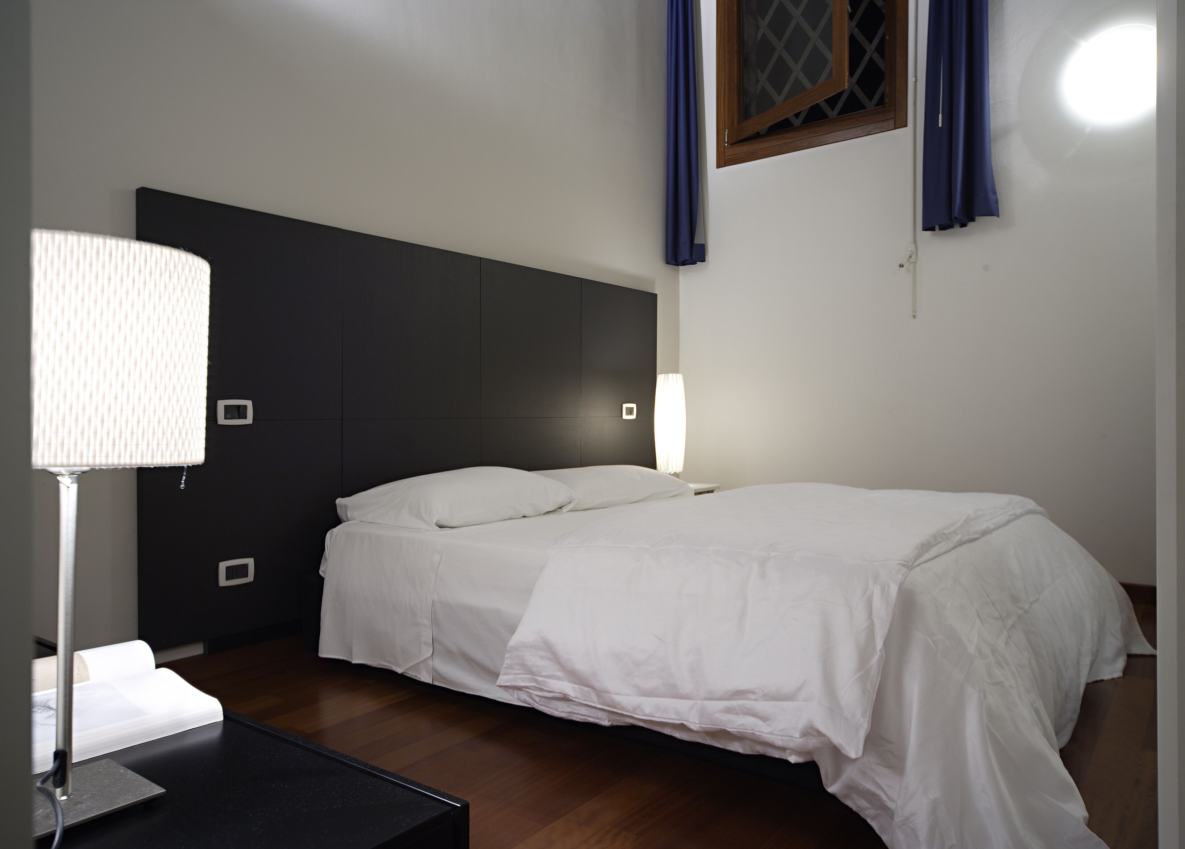 Une chambre à coucher moderne avec un lit, des lampes de chevet et une fenêtre avec des rideaux.