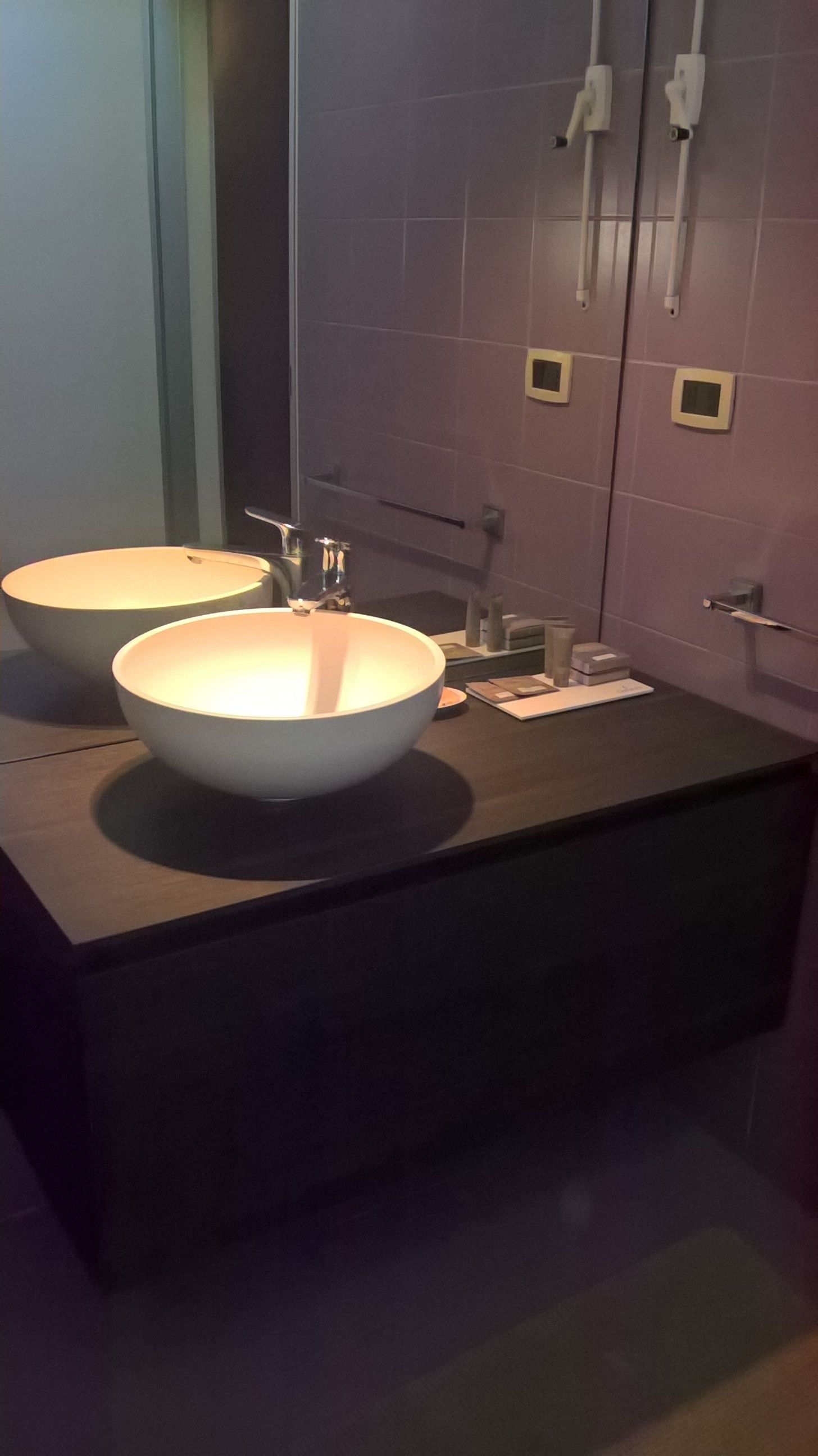 A bathroom with two large white sinks, a dark countertop, and a mirror.