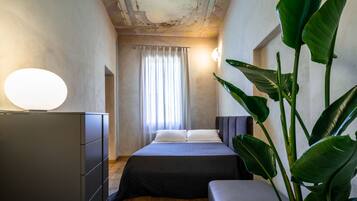 Un dormitorio moderno con cama, cómoda, mesita de noche y una planta grande.
